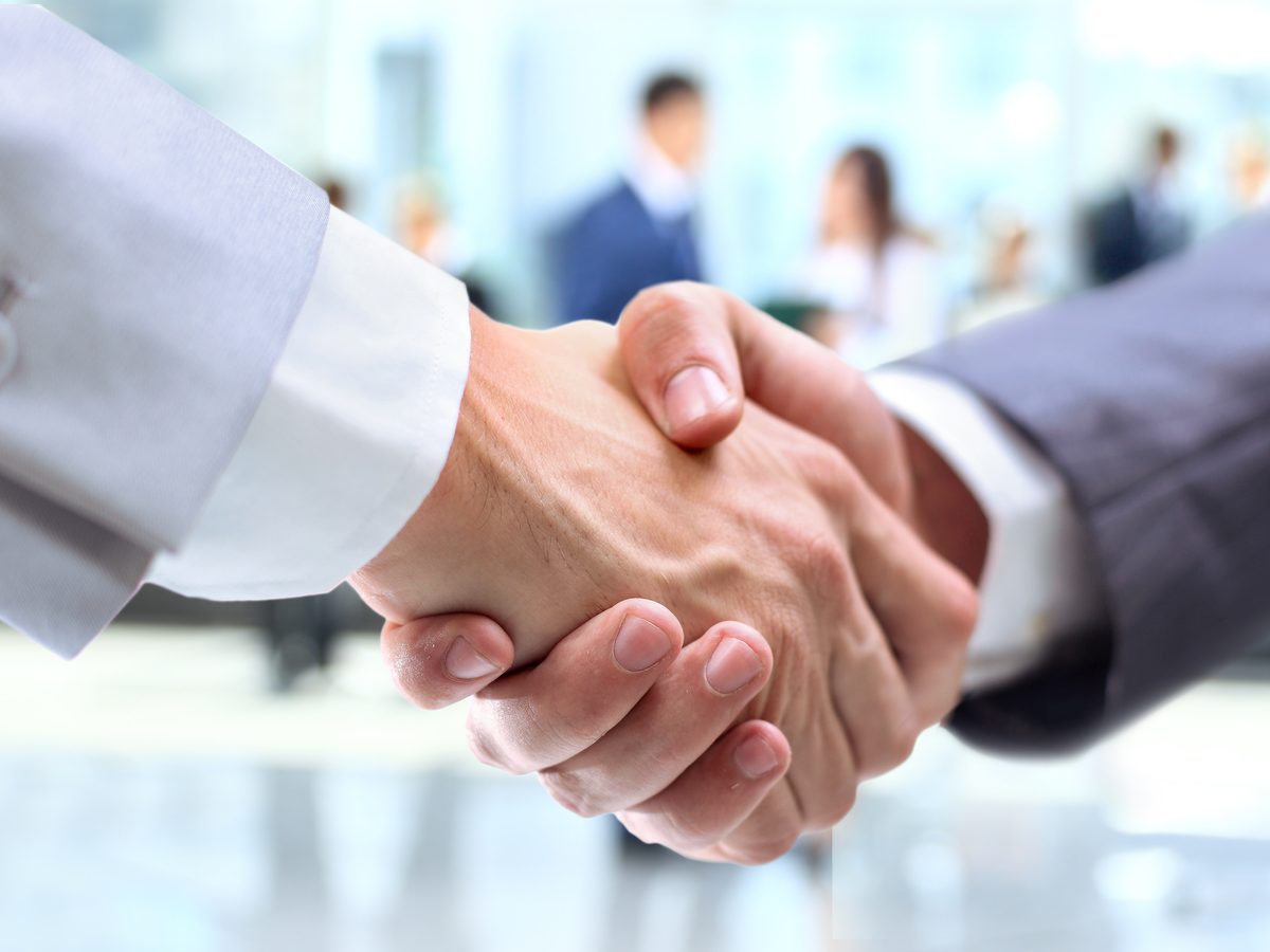 Two business people shaking hands in a bright office lobby
